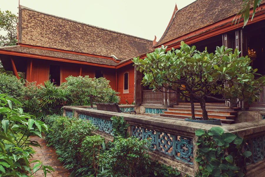 Une maison traditionnelle thaïe en teck au milieu d'un jardin tropical